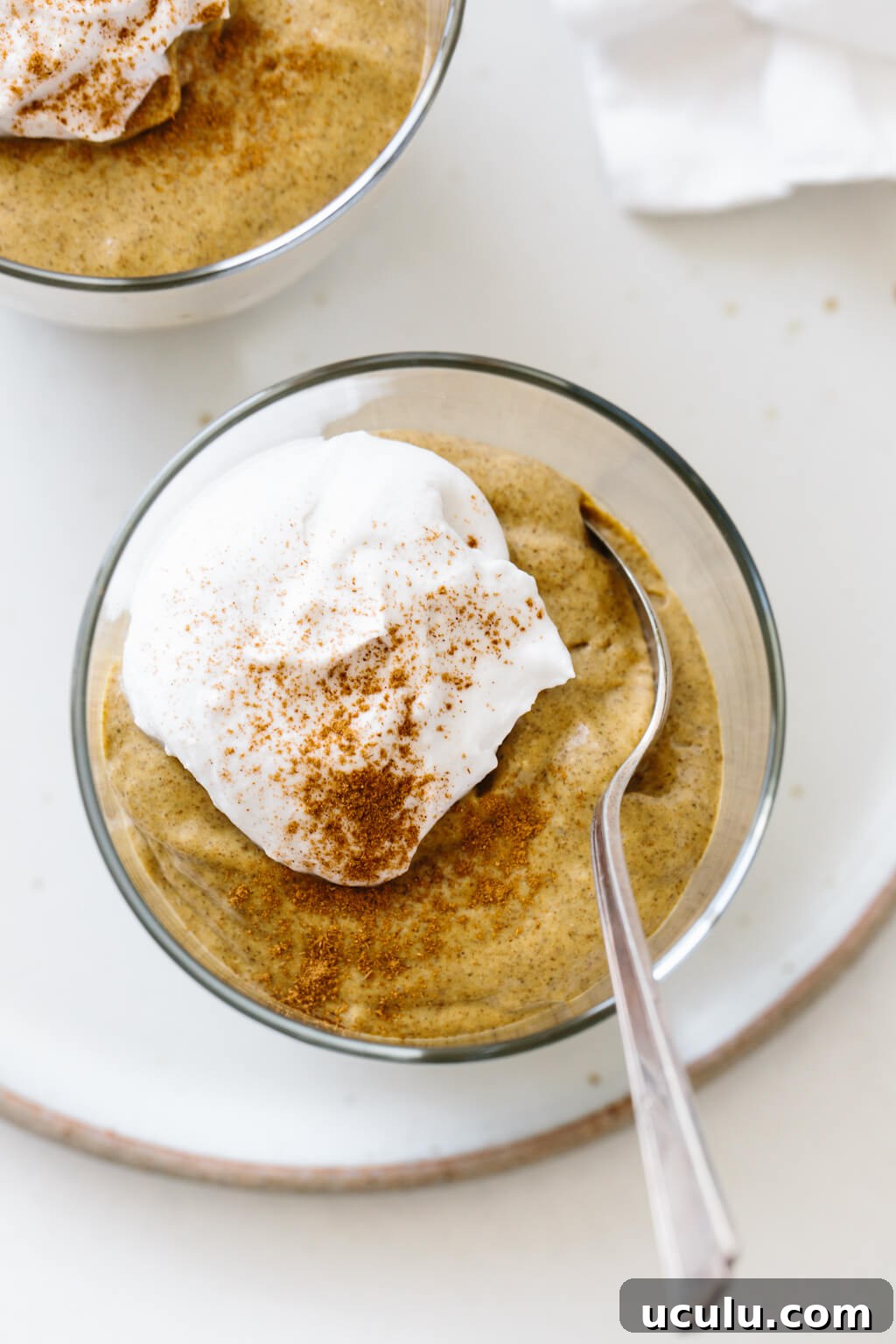 Pumpkin chia pudding in a glass jar with a dollop of whipped cream and cinnamon.