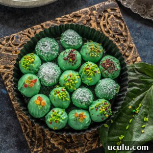 green color balls coated with candied fennel placed in a round plate with paan leaves and some tealights placed on the sides