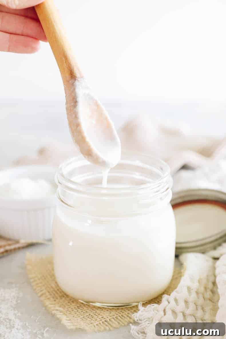 Drippy coconut butter in a mason jar with a wooden spoon.