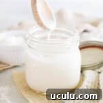 homemade coconut butter in a mason jar with a drippy wooden spoon.