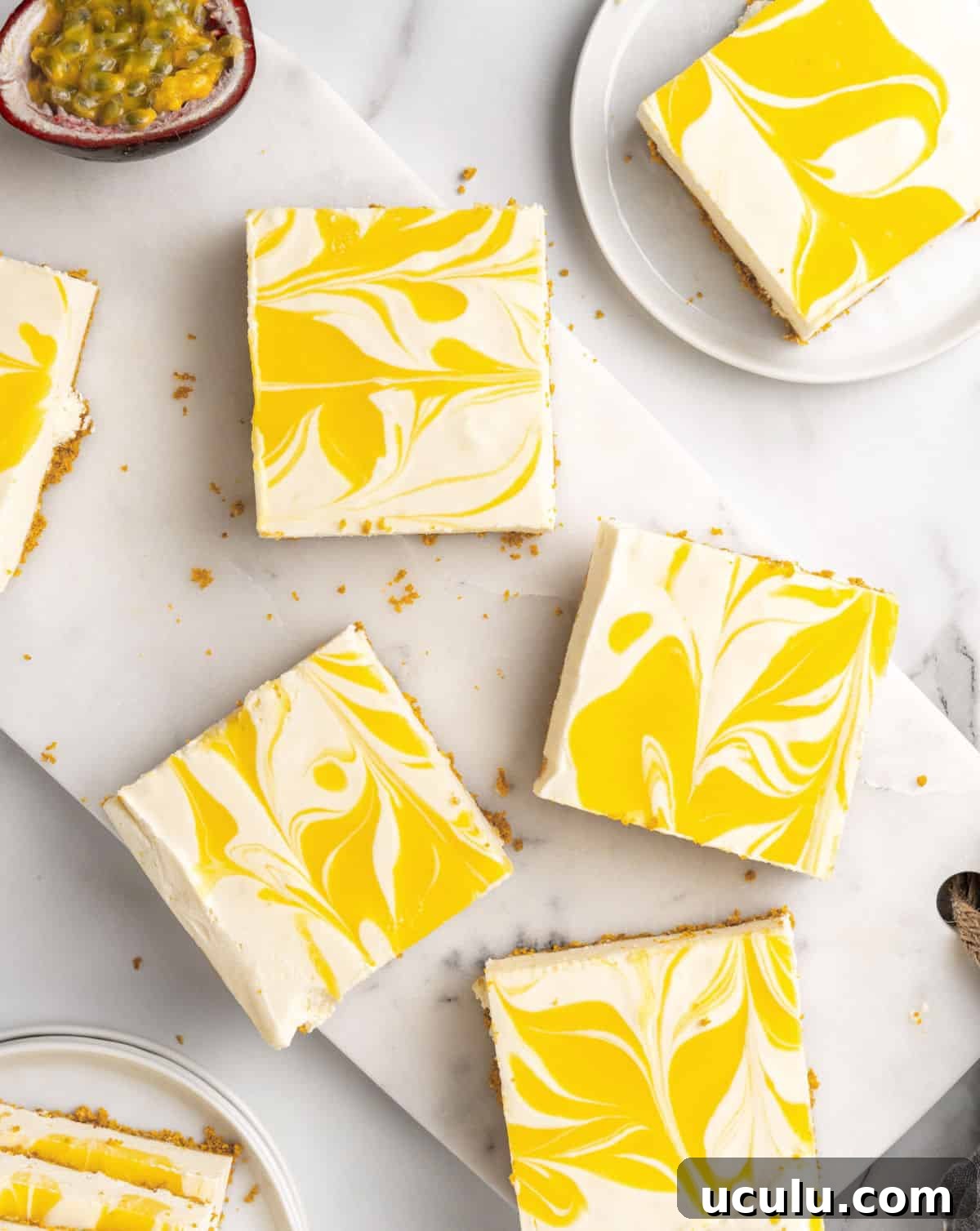Squares of passion fruit no-bake cheesecake on a white marble surface. Top view. 
