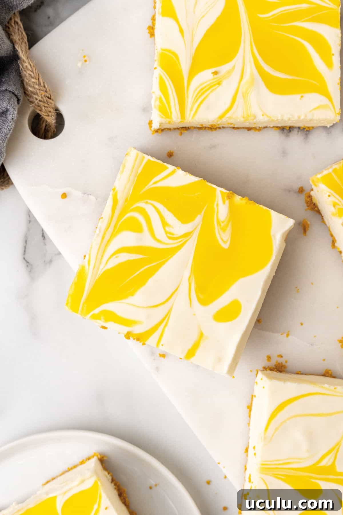 Marbled passionfruit cheesecake squares on a white marble board. 