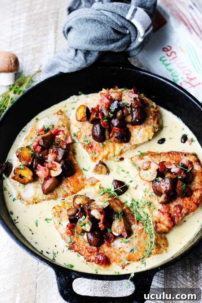 Pork Chops in white wine cream sauce with mushrooms and bacon in the pan with bacon on a side