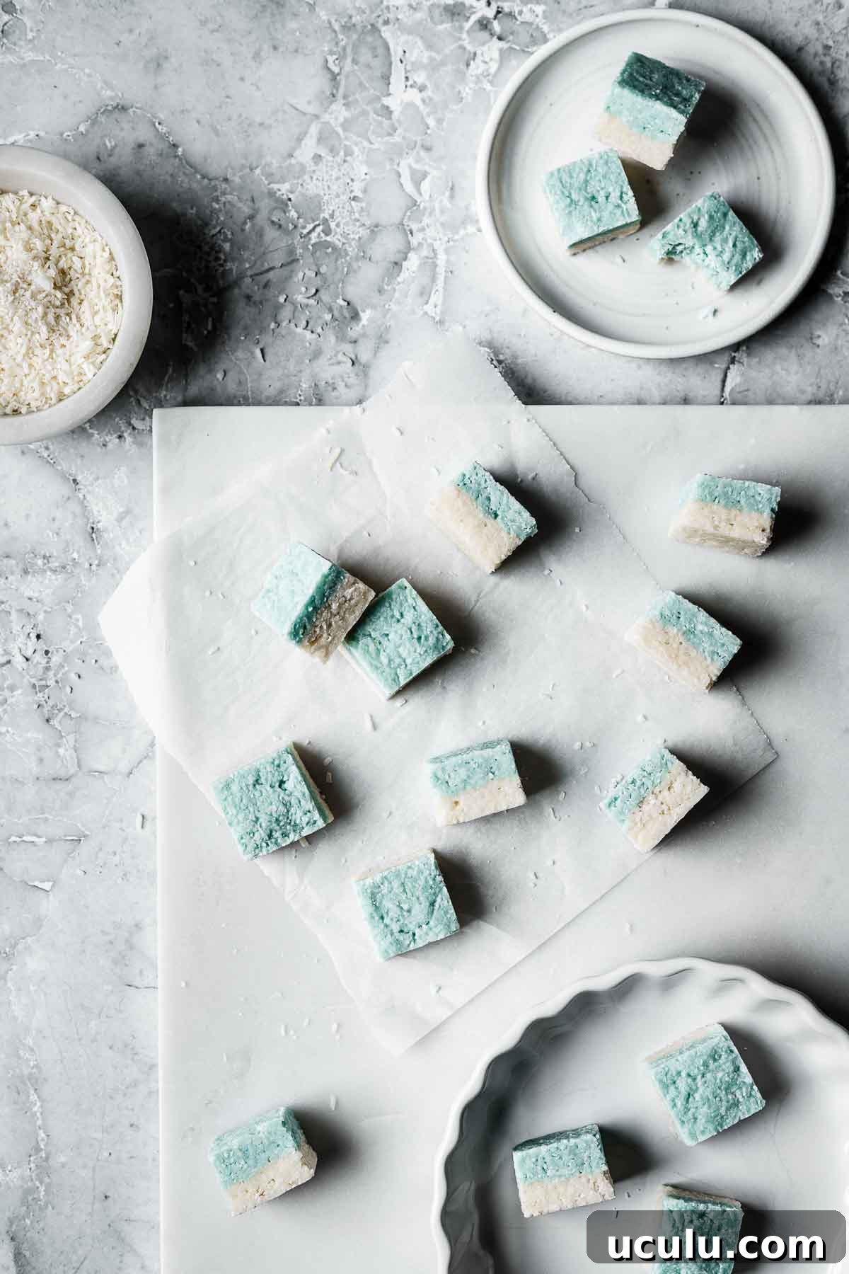 Squares of coconut candy on a white marble tray.