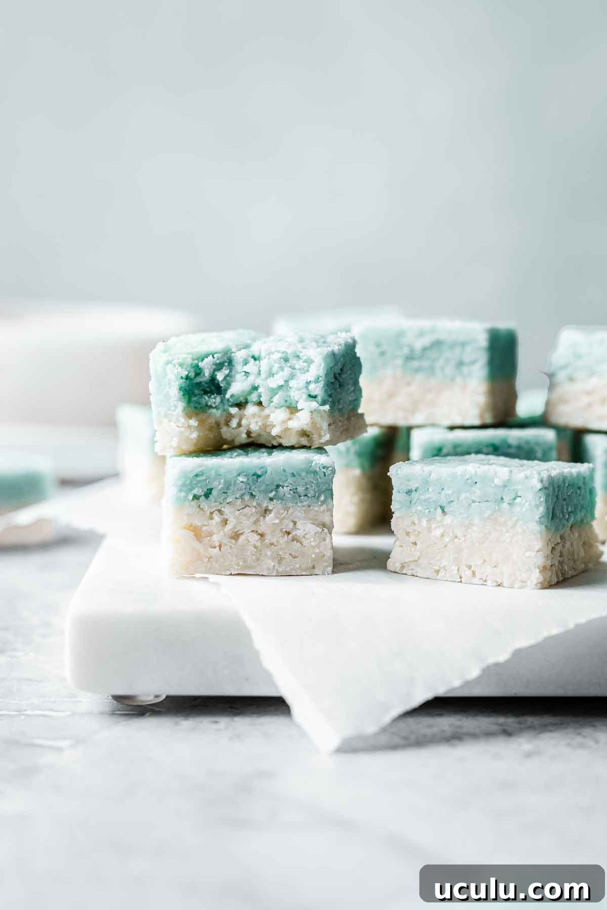 Squares of blue and white coconut ice stacked up with a bite out of one.