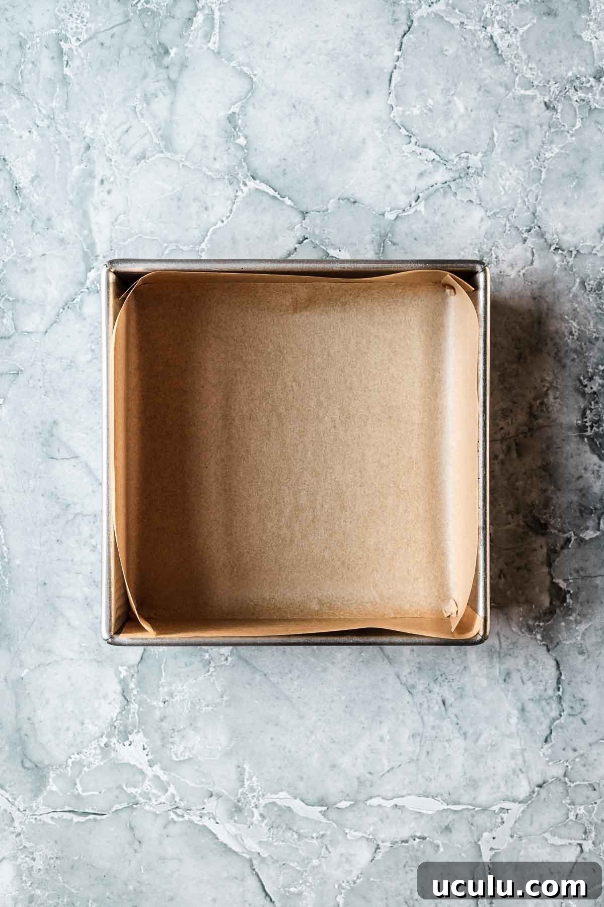 A square baking pan lined with parchment paper.