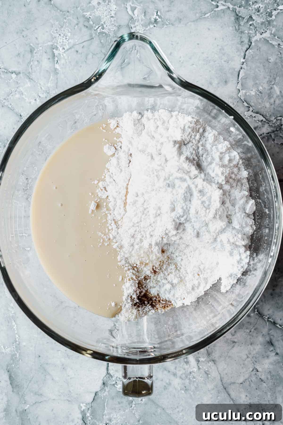 Ingredients for coconut ice recipe in a glass mixing bowl.