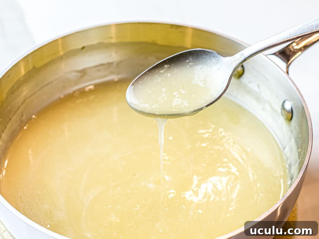 clear Chinese stir fry sauce poured off a spoon into a pot