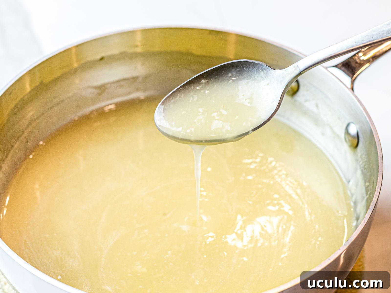 clear Chinese stir fry sauce poured off a spoon into a pot