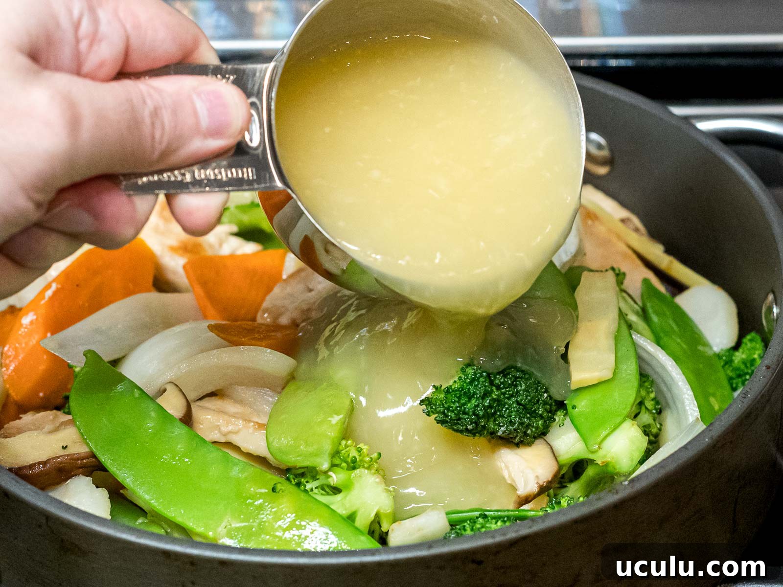 Moo goo gai pan sauce being added to chicken and vegetables stir fry