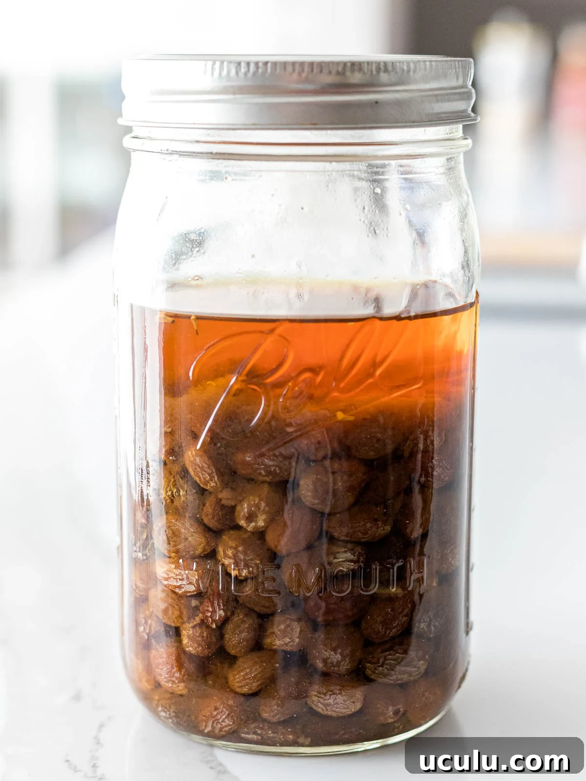 raisins sitting in water inside a glass mason jar with a screw top lid
