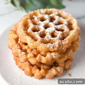 Stacked rosette cookies on a white plate with holly