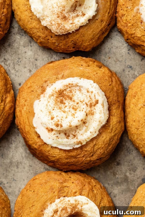 A baking sheet with pumpkin cookies topped with cream cheese frosting and cinnamon.