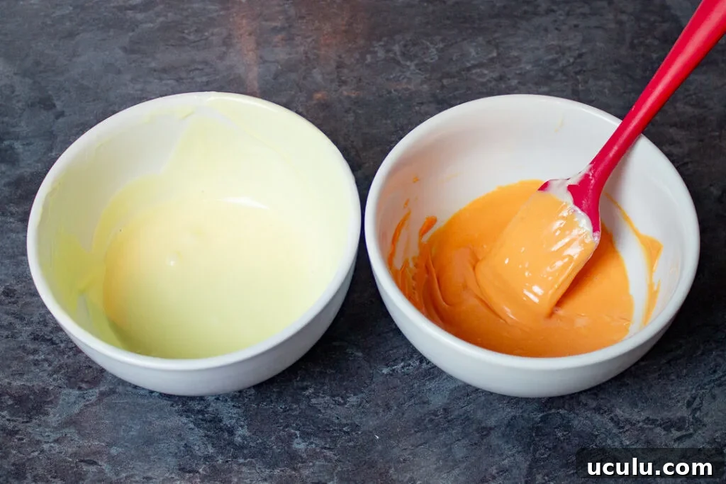 Two bowls, one with melted white chocolate, and another with melted white chocolate dyed orange.