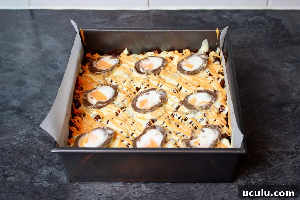 Creme Egg halves pressed into the top of the rocky road mixture in a baking tin.