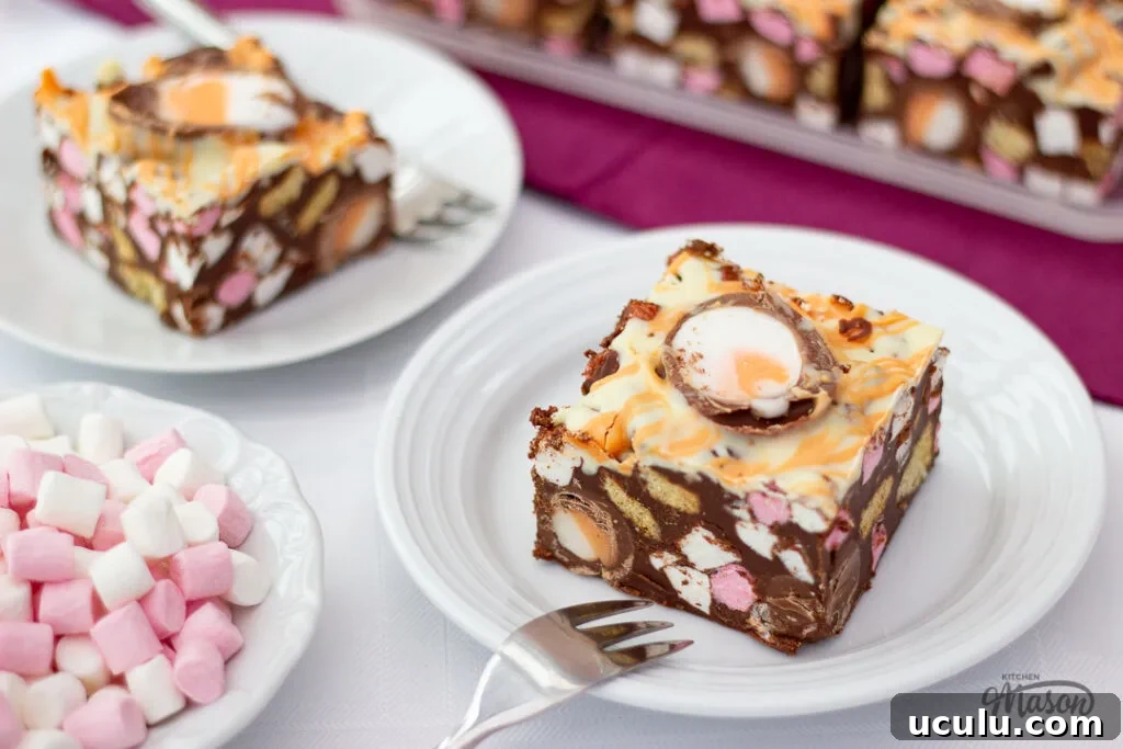 Two Creme Egg rocky road bars on white plates, with a bowl of mini marshmallows to the side.