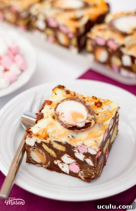 Close up of a Creme Egg rocky road bar on a small white plate with a fork.