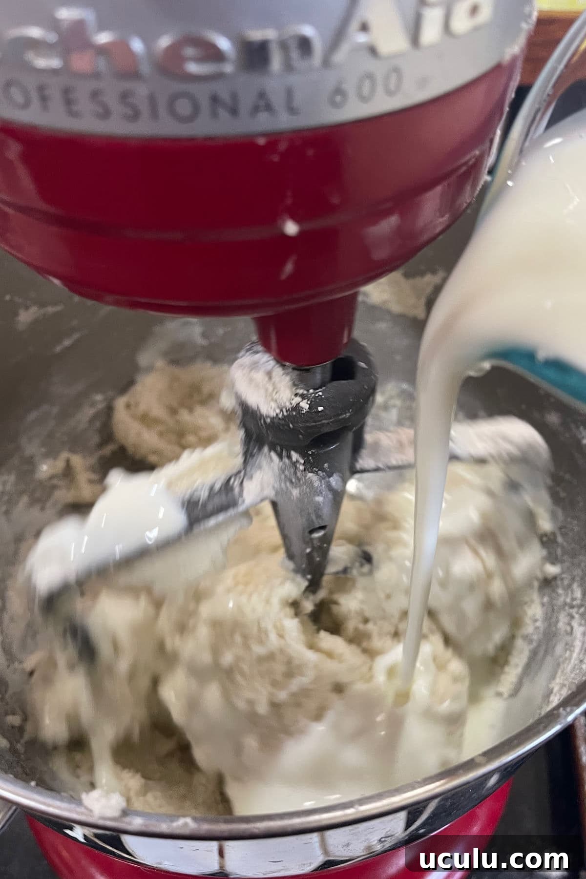 Buttermilk is being added to the mixer bowl.
