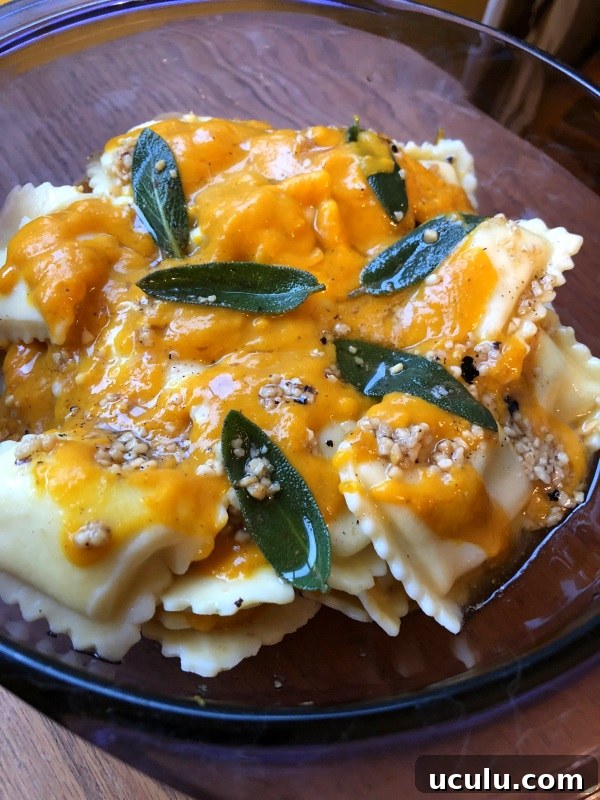 Pumpkin sauce with sage leaves in brown butter over cheese ravioli in a purple serving dish from ApronFreeCooking