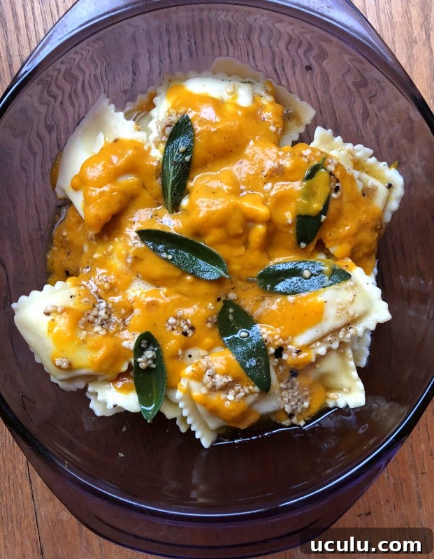Pumpkin sauce with sage leaves in brown butter over cheese ravioli in a purple serving dish from ApronFreeCooking
