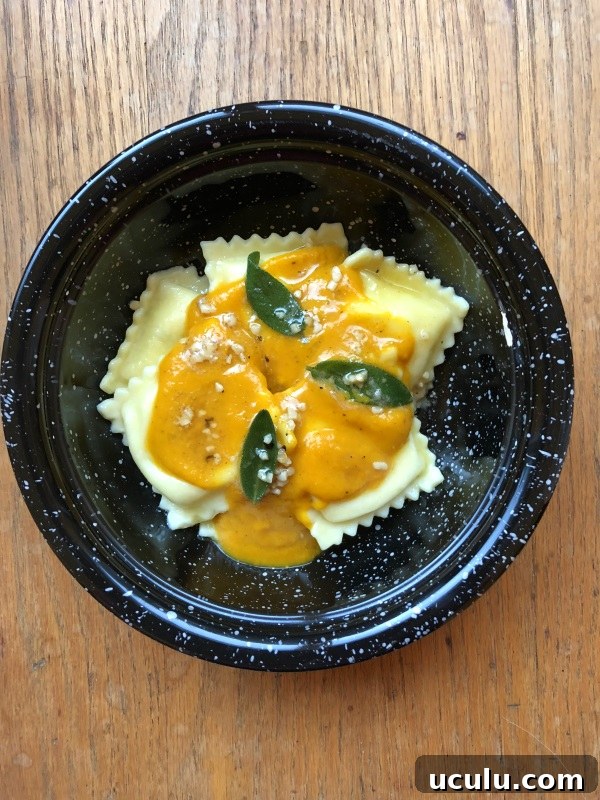 Pumpkin sauce with sage leaves in brown butter over cheese ravioli served in a black bowl from ApronFreeCooking