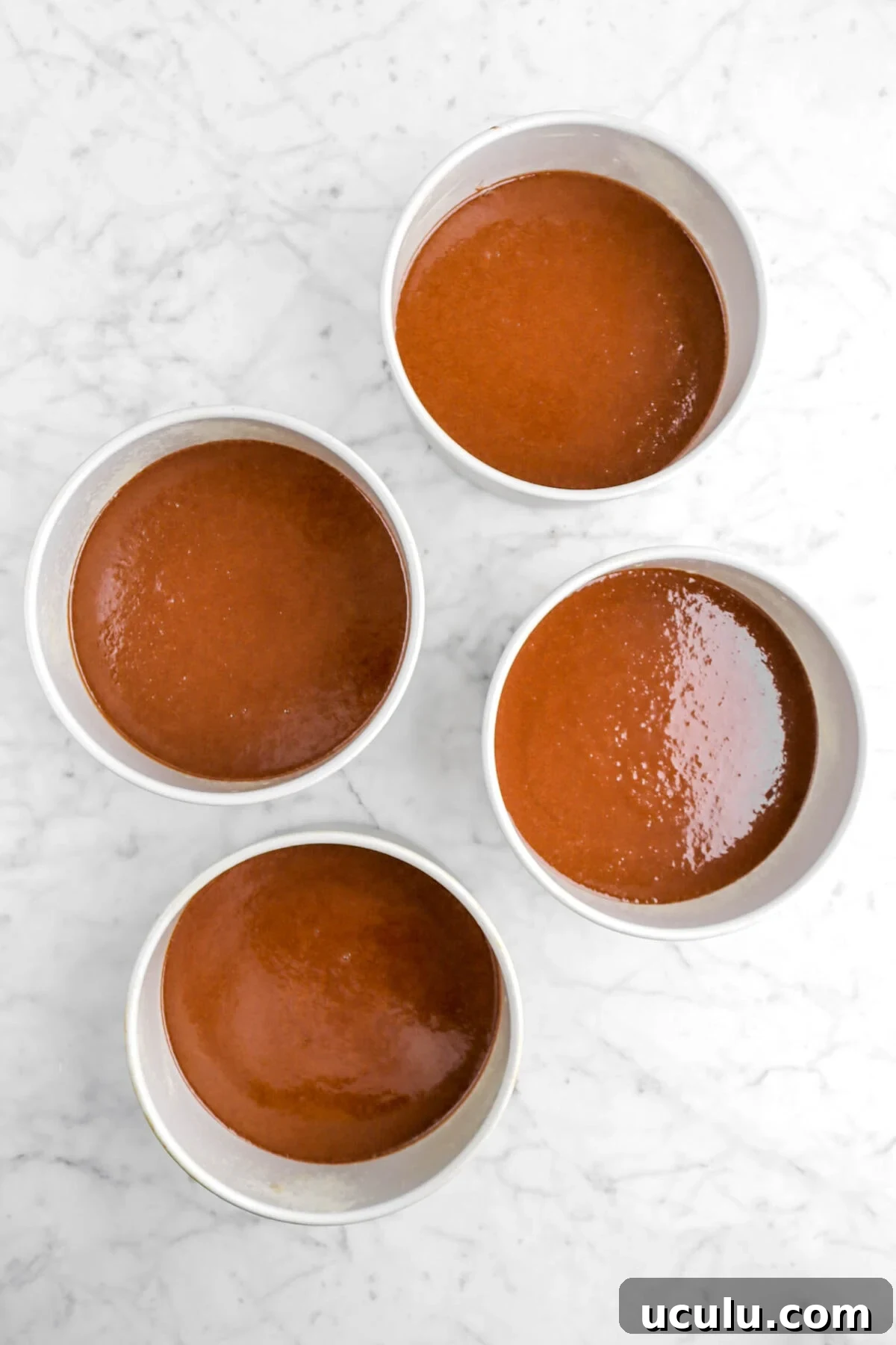 chocolate cake batter divided among 4 cake pans