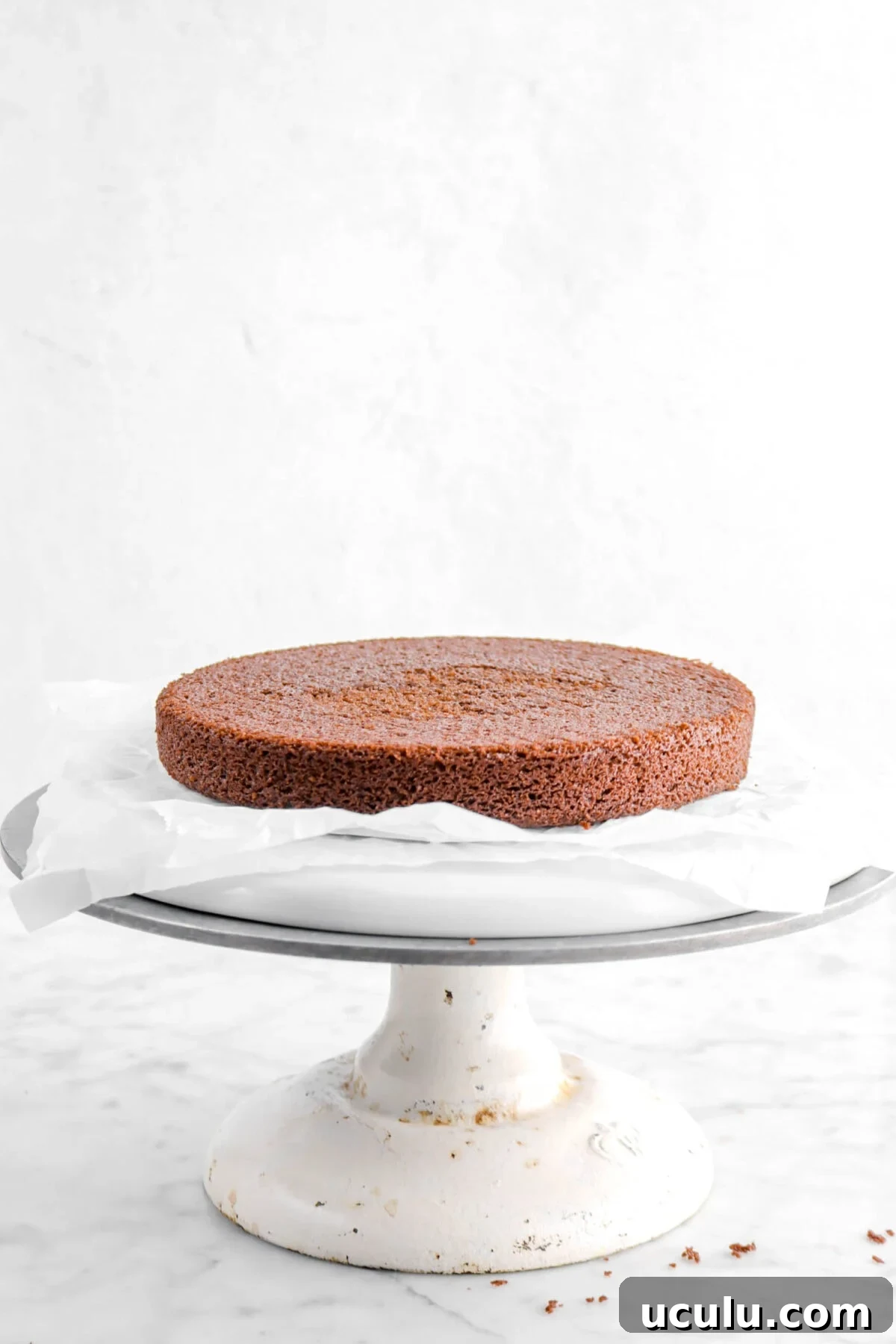 chocolate cake layer on parchment paper on a cake stand