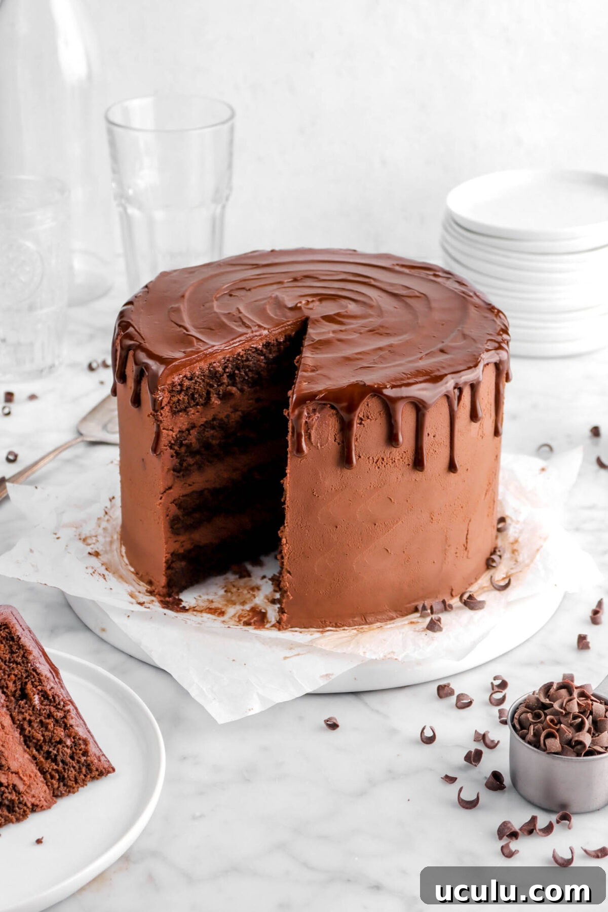 chocolate cake on parchment paper with slice of cake beside on white plate