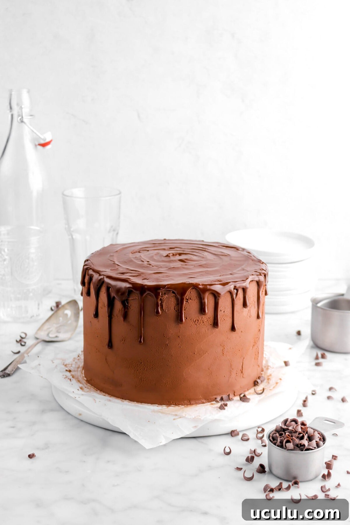 chocolate cake with chocolate drips on white plate with chocolate curls around and cake knife