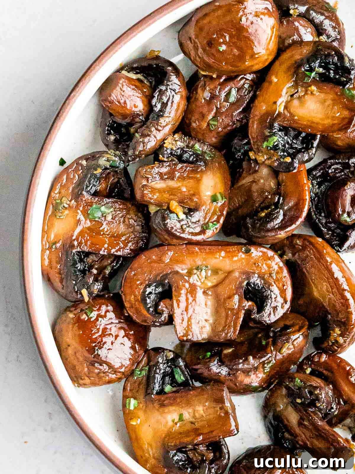 overhead of golden brown sauteed mushrooms with garlic and chopped parsley
