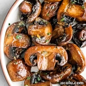 close up of sauteed mushrooms with garlic butter and chopped parsley in a white bowl
