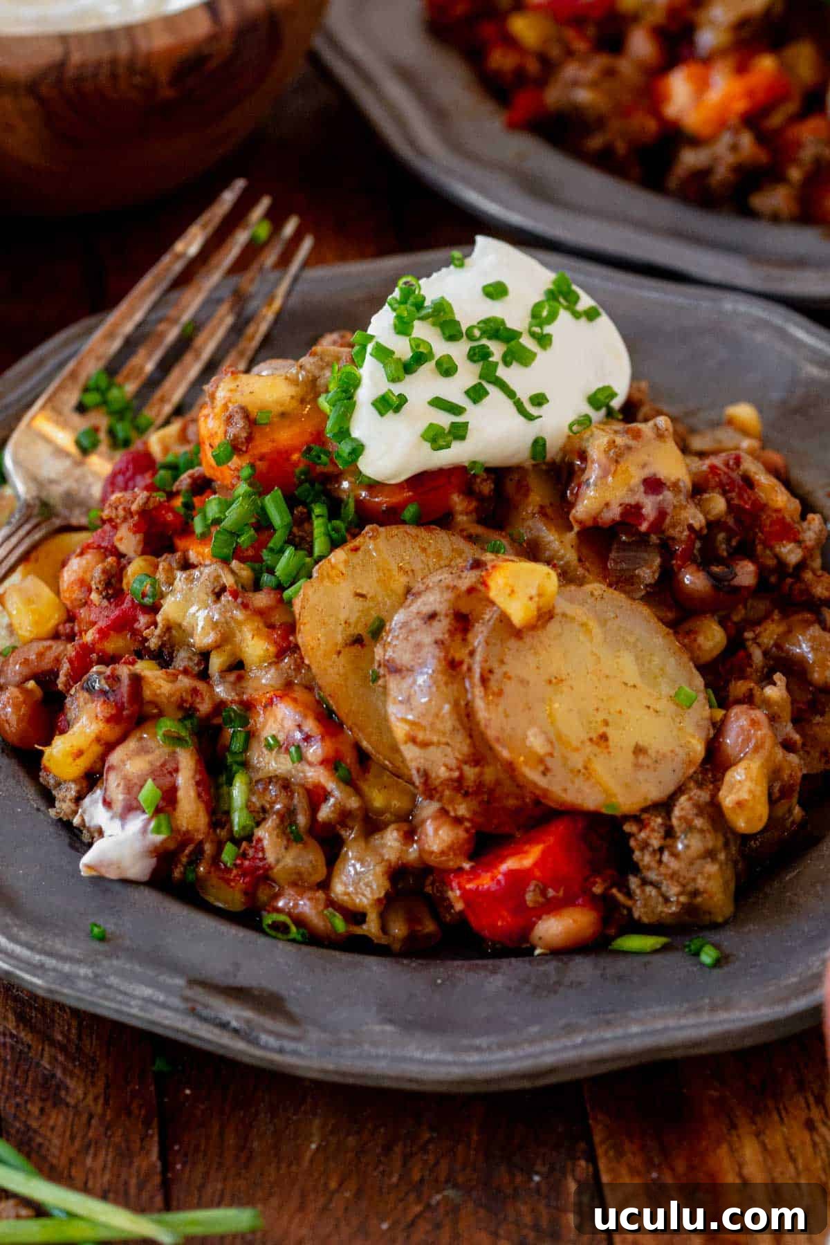 a plate of cowboy casserole with sour cream and melted cheese.