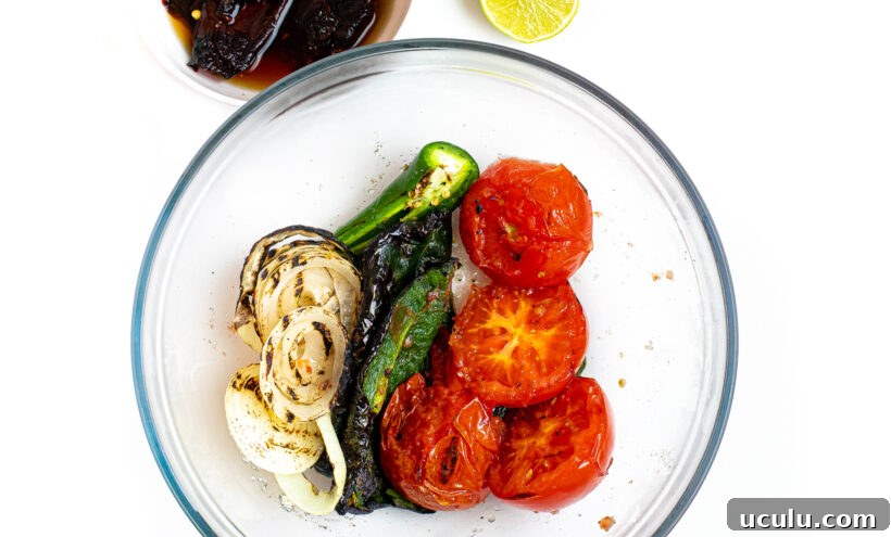 Roasted veggies for salsa in a glass mixing bowl.