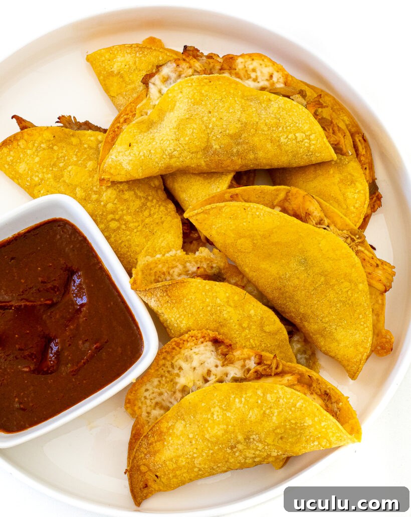 Crispy Baked Chicken Tacos on a plate next to a bowl of salsa.