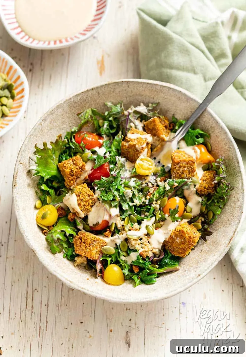 Close up shot of Comforting Tempeh Kale Salad in a ceramic bowl with fork
