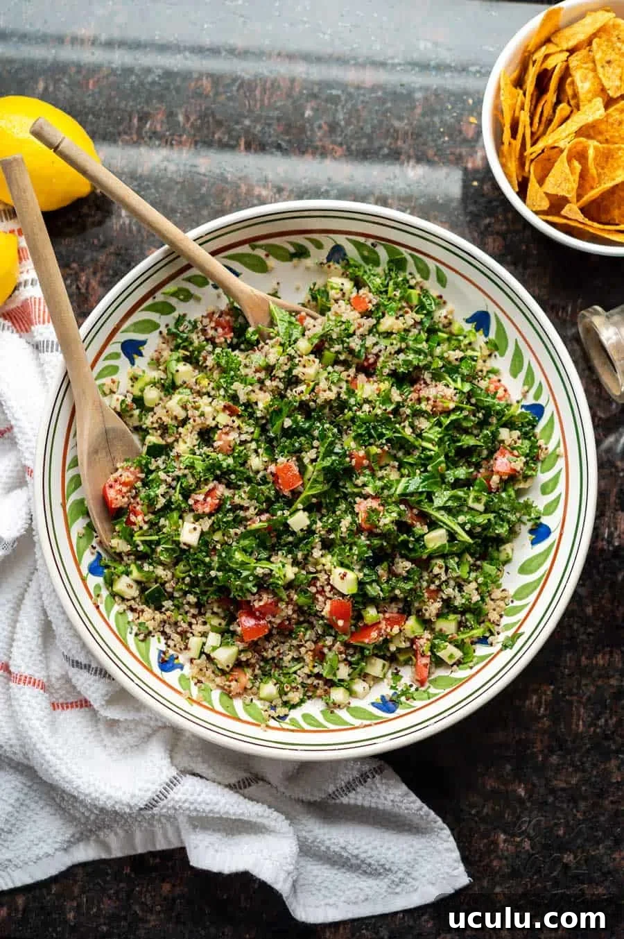 Image of kale quinoa tabbouleh salad in a large ceramic bowl, on granite countertop.