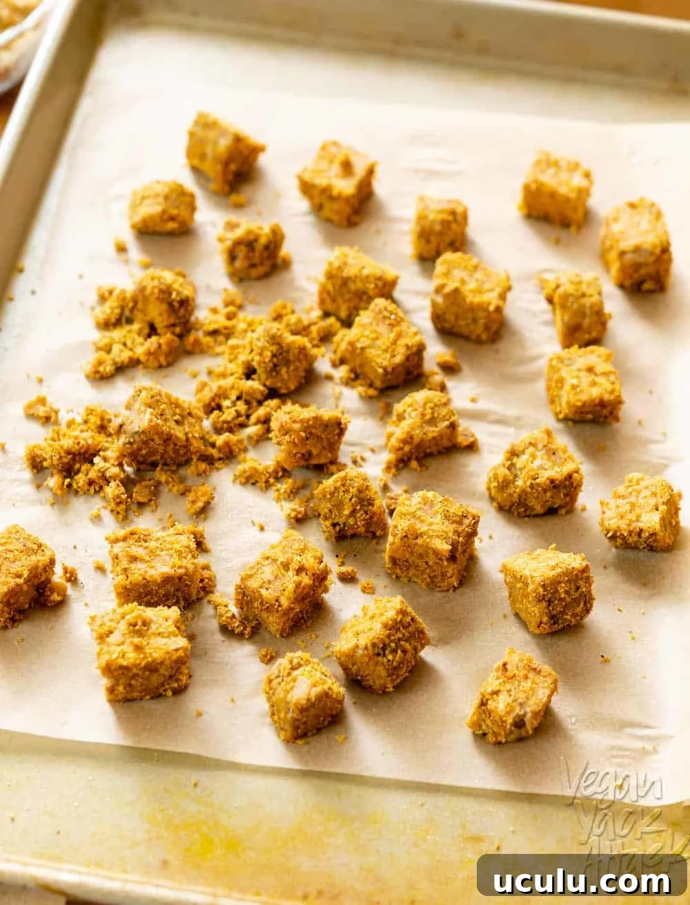 Sheet pan with parchment paper and coated tempeh before roasting