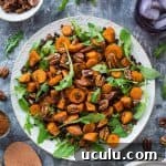 A plate of vegan roasted sweet potato, lentil and rocket salad with toasted pecans and pomegranate molasses dressing