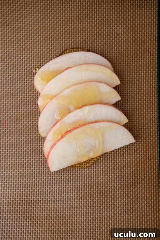 Apple slices and honey on baking sheet