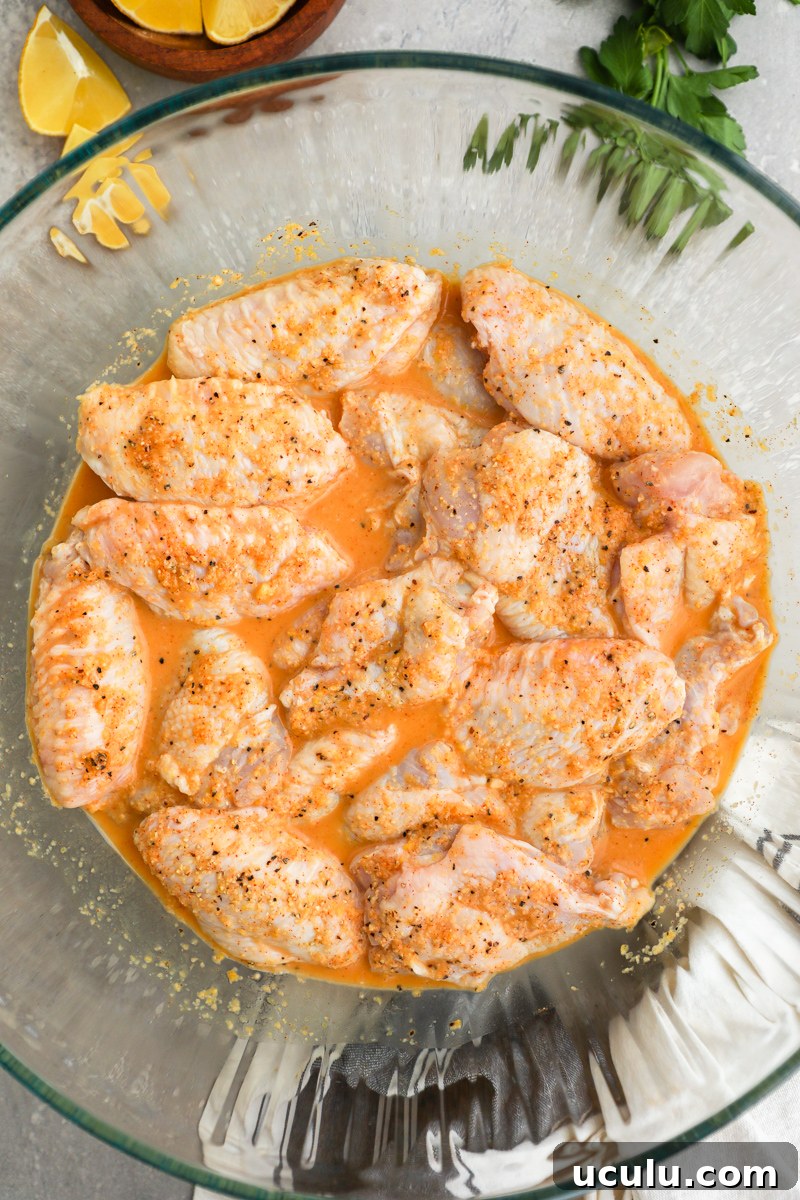 A large clear bowl filled with chicken wings marinating in a lemon garlic mixture