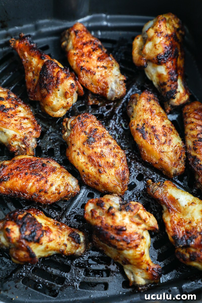 A close up photo of crispy marinated lemon garlic chicken wings in an air fry basket