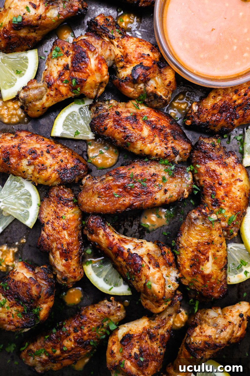 A close up photo of lemon garlic chicken wings sitting next to a small bowl of marinade that doubles as a dipping sauce.