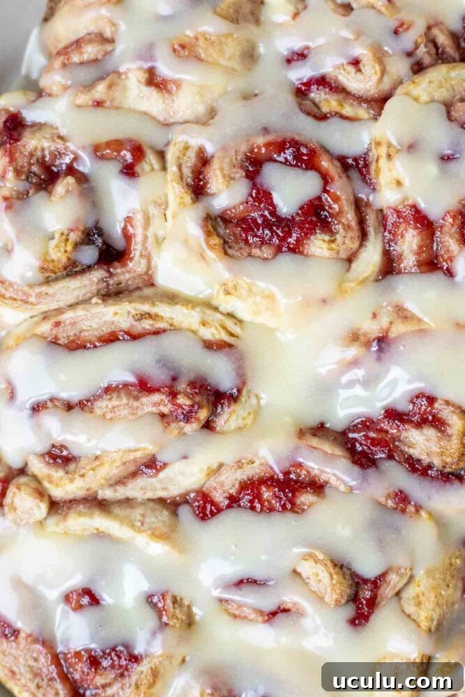 close up of strawberry sourdough rolls drizzled with cream cheese icing