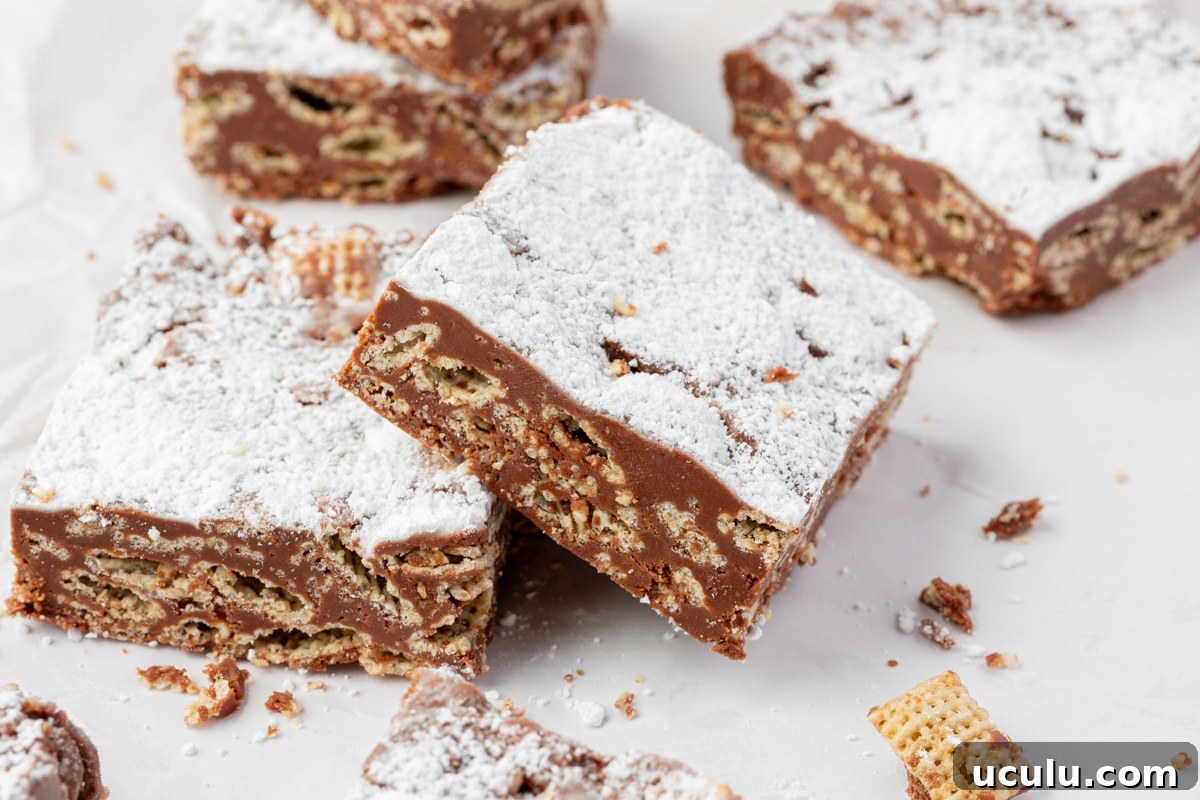 Sliced chocolate cereal bars arranged on parchment paper with crumbs around.