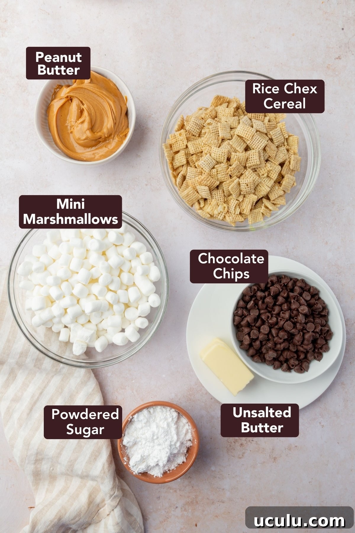 Ingredients for puppy chow bars including peanut butter, Chex cereal, mini marshmallows, chocolate chips, butter, and powdered sugar in labeled bowls.