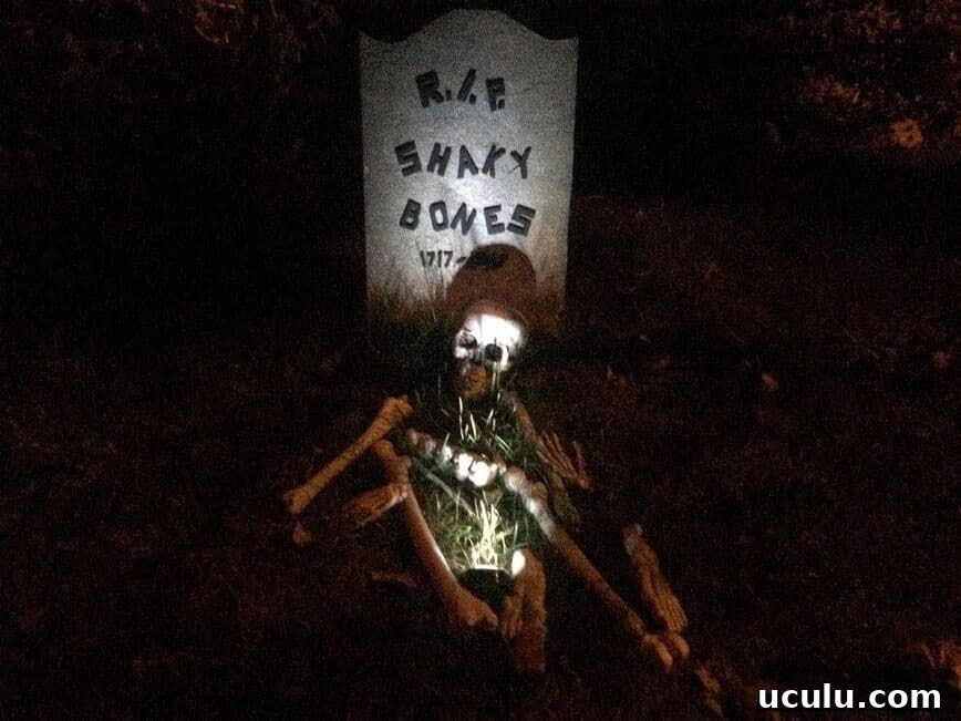 RIP Shaky Bones tombstone, with skeleton on ground.