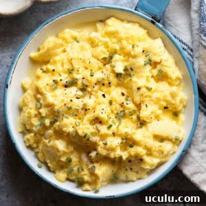 Overhead close up of scrambled eggs in a blue skillet.
