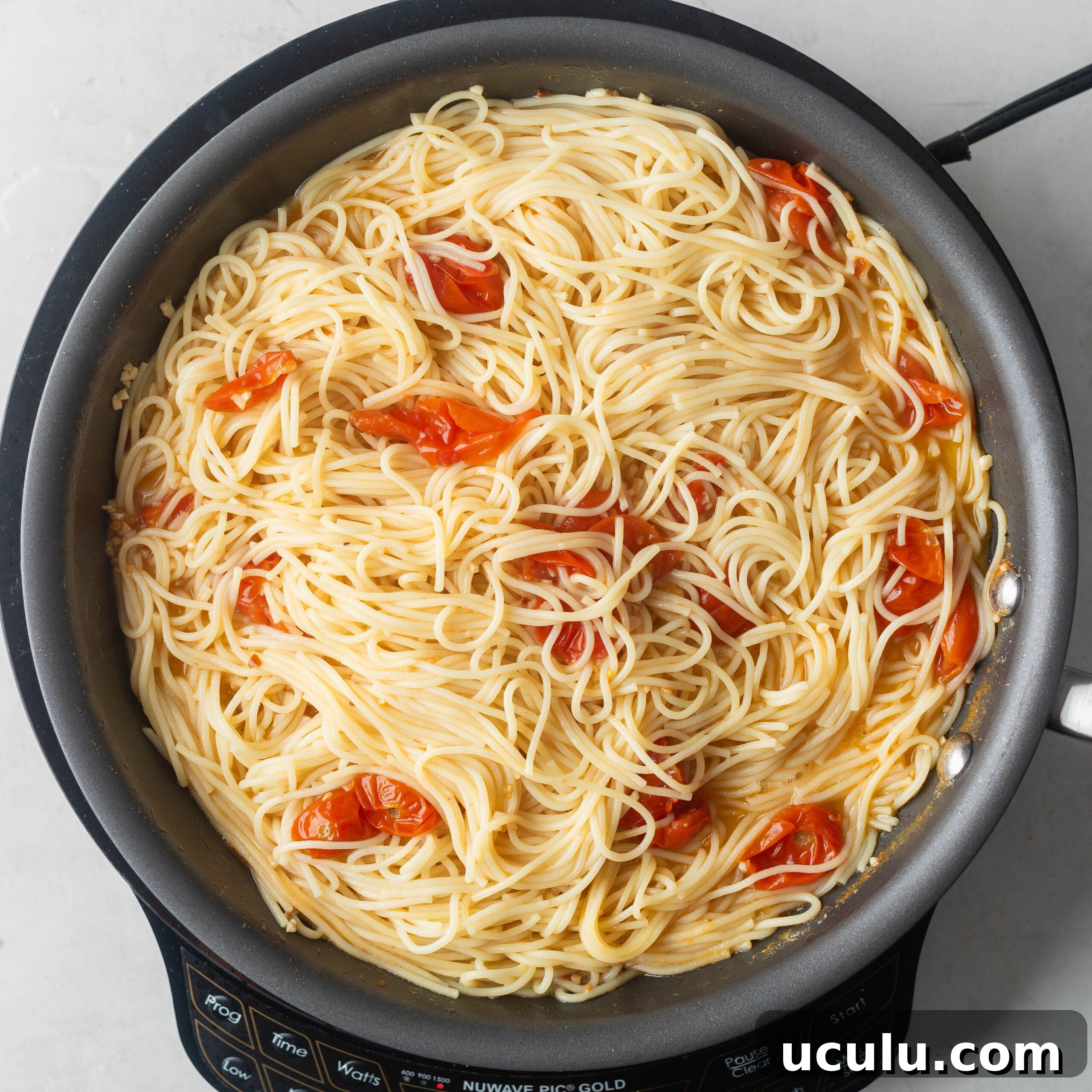 Mixing pasta into scampi sauce to coat noodles.