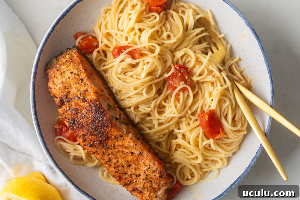 Bowl of Angel hair pasta with garlic butter scampi sauce and a cooked piece of salmon.