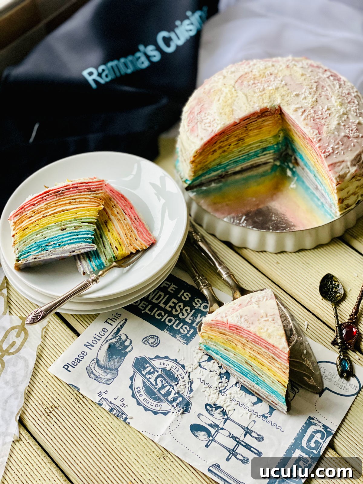 Two rainbow crepe cake slices on a stack of white plates and one slice closer on a patterned black and white paper
